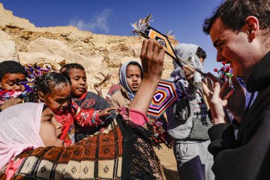 Siwa Oasis, Mısır Büyük İskender 'in taç giyme töreninde yerel çocuklardan ev yapımı incik boncuklar alan bir turist..
