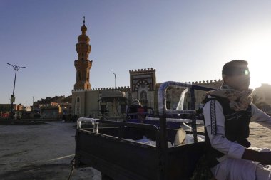 Siwa Oasis, Mısır Bir adam ana meydanda motosiklet sürüyor Cami ile dolu bir kamyonun yanında.