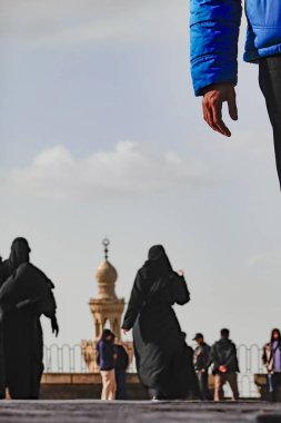 Kahire, Mısır Turistleri Muhammed Ali Camii 'nin ve arka planda Mescid-i Mahmûdîye Camii minaresinin bahçesinde yürüyorlar..