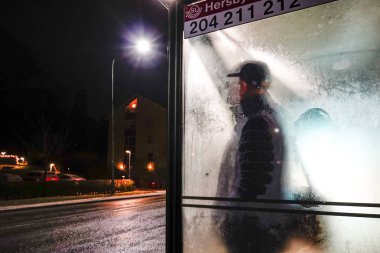 Stockholm, İsveç Banliyöde soğuk bir otobüs durağında duran bir adam.