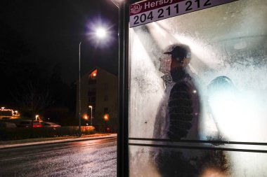 Stockholm, İsveç Banliyöde soğuk bir otobüs durağında duran bir adam.
