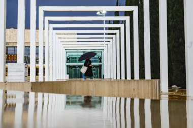 Tel Aviv, Israel A person walking on Ha-bima Square with an umbrella.