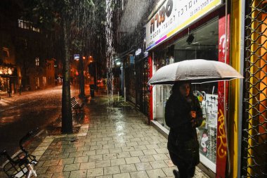 Tel Aviv, Israel A pedestrian with an umbrella in a heavy downpour on King George Street.