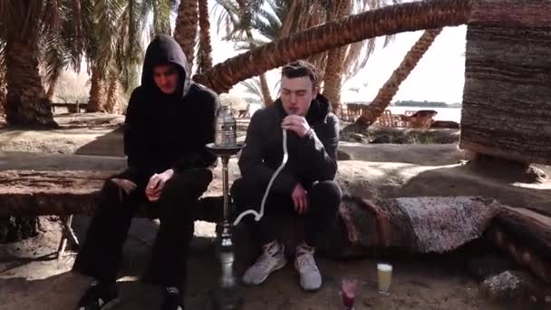 Siwa Egipto Dos Turistas Jóvenes Fumando Una Pipa Agua — Vídeos de Stock