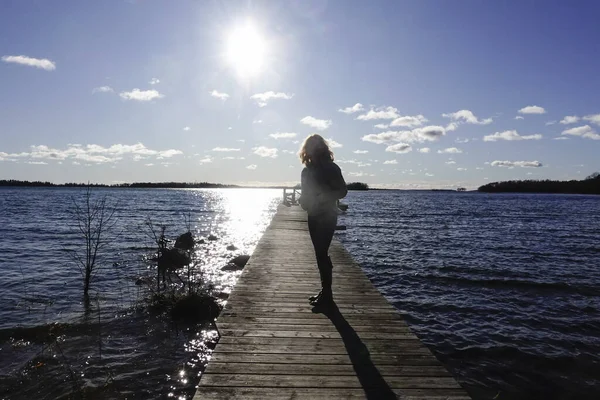 スウェーデンのノルトラジェバルト海の桟橋で一人で太陽の下を歩く女性 — ストック写真