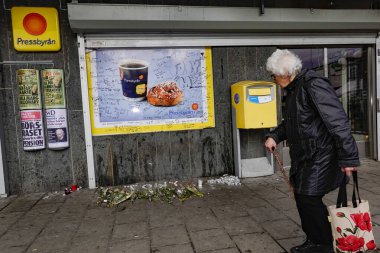 Stockholm, İsveç 10 Mart 2020 Fruangen banliyösünde yaşlı bir kadın çiçeklerin ve mesajların yanından geçerek vurularak öldürülen bir adam için geçiyor..