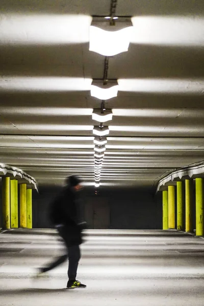 Stockholm, Sweden  A  man walks in a parking garage at night with no cars.