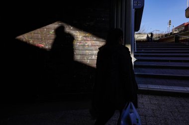 Stockholm, İsveç Bredang banliyösünde bir yaya ve güçlü bir güneş ışığı ve gölge huzmesi.