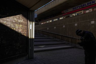 Stockholm, İsveç Bredang banliyösünde bir yaya ve güçlü bir güneş ışığı ve gölge huzmesi.