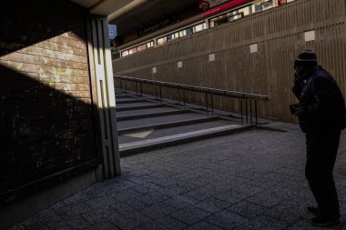 Stockholm, İsveç Bredang banliyösünde bir yaya ve güçlü bir güneş ışığı ve gölge huzmesi.