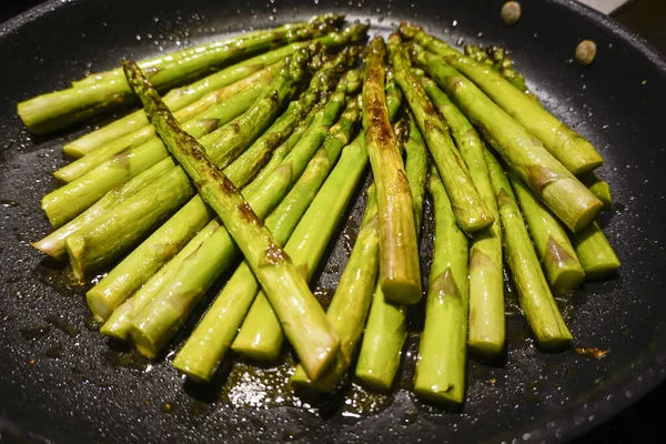 Fresh green asparagus frying in a pan with olive oil