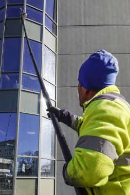 Stockholm, İsveç 'te bir cam silici yüksek pencerelere ulaşmak için uzun bir direk kullanır..