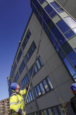Stockholm, İsveç 'te bir cam silici yüksek pencerelere ulaşmak için uzun bir direk kullanır..