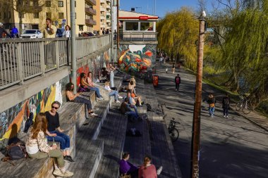 Stockholm, Sweden People enjoy the warm spring weather as they sit in the Hornstull neighborhood during the COVID-19 pandemic. clipart