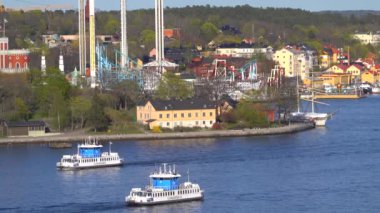 Stockholm, İsveç 27 Nisan 2020 Küçük yolcu feribotları Skeppsholmen ve Grona Lund Lund lunaparkından geçiyor. 