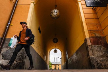 Norrkoping, İsveçli yayalar şehrin eski ikonik değirmen ve sanayi bölgesinde ve Jarnbrogatan 'da bir geçitte yürüyorlar..