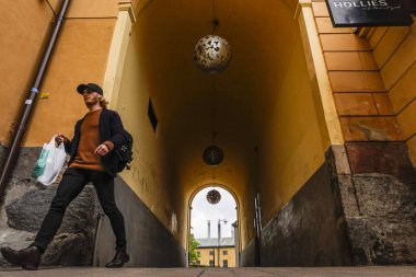 Norrkoping, İsveçli yayalar şehrin eski ikonik değirmen ve sanayi bölgesinde ve Jarnbrogatan 'da bir geçitte yürüyorlar..