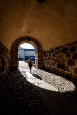 Kalmar, İsveçli yayalar tarihi su kulesinin altındaki eski bir kaldırım taşlı sokakta yürüyorlar..