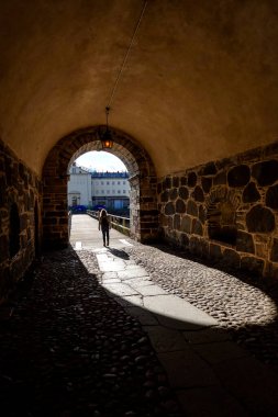 Kalmar, İsveçli yayalar tarihi su kulesinin altındaki eski bir kaldırım taşlı sokakta yürüyorlar..