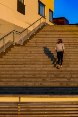 İsveç 'in Kalmar kentinde, Varvsholmen adlı modern bir deniz kenarı mahallesinde bir kadın merdivenleri tırmanıyor..