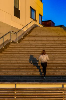 İsveç 'in Kalmar kentinde, Varvsholmen adlı modern bir deniz kenarı mahallesinde bir kadın merdivenleri tırmanıyor..