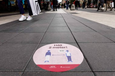 Stockholm, İsveç. 16 Mayıs 2020. Meşgul bir alışveriş caddesi olan Drottninggatan 'ın tabelasına göre İsveçliler birbirine iki metre uzak dursun..