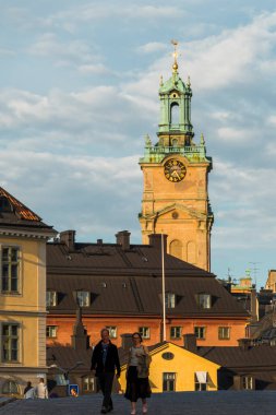 Stockholm, İsveç Riddarholmen adasında yürüyen bir çift ve Gamla Stan 'deki Alman Kilisesi manzarası.