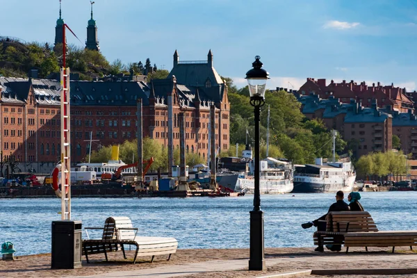 ストックホルム スウェーデン二人はソダーマルムに水の上を見てリダーホルメンのベンチに座っている — ストック写真