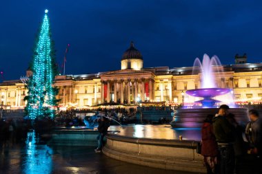 Londra, Uk / Avrupa; 20 / 12 / 2019: Ulusal Galeri 'nin gece manzarası ve Londra' daki Trafalgar Meydanı 'nda bir Noel ağacı. Bulanık insanların yürüdüğü uzun pozlar..