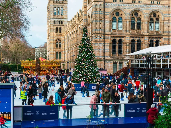 London, uk / europa; 21.12.2019: eisbahn und weihnachtsbaum im naturkundemuseum in london. Menschen genießen das Schlittschuhlaufen an Weihnachten vor einem der berühmtesten Museen der Stadt. — Stockfoto