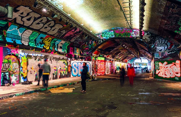 Londres, Reino Unido / Europa; 21 / 12 / 2019: Leake Street, túnel subterráneo con paredes cubiertas de graffiti en Londres. Escena con peatones y grafiteros . — Foto de Stock