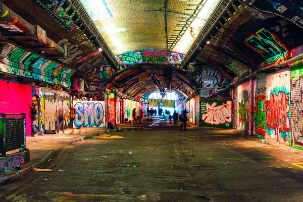 Londres, Reino Unido / Europa; 21 / 12 / 2019: Leake Street, túnel subterráneo con paredes cubiertas de graffiti en Londres. Escena con peatones y grafiteros . — Foto de Stock