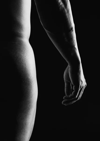 Detail of muscular man arm and buttocks against a black background — Stockfoto