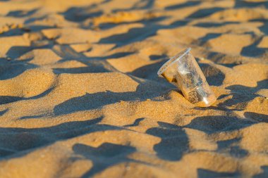 Okyanusun altın kumsalındaki değersiz plastik bardak, Playa de las Teresitas, Tenerife. Çevre koruma kavramı. Plastik atıkla okyanuslar kirleniyor. Geri Dönüşüm.