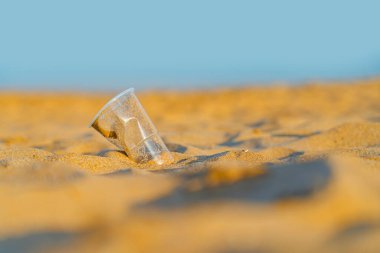 Okyanusun altın kumsalındaki değersiz plastik bardak, Playa de las Teresitas, Tenerife. Çevre koruma kavramı. Plastik atıkla okyanuslar kirleniyor. Geri Dönüşüm.