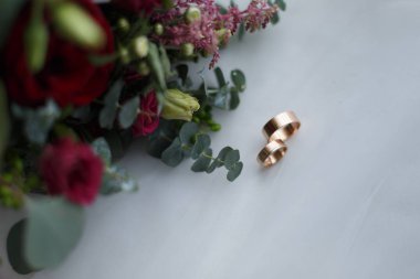 Alyanslar ve gelinlik buketi beyaz arka planda.