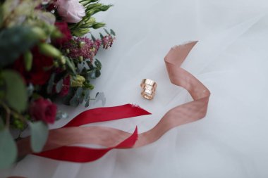 Alyanslar ve gelinlik buketi beyaz arka planda.