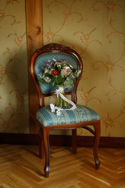 Bukiet ślubny stoi na zabytkowym krześle — Zdjęcie stockowe