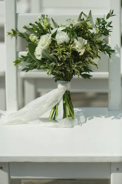 Buquê de casamento branco da noiva fica em uma cadeira branca — Fotografia de Stock