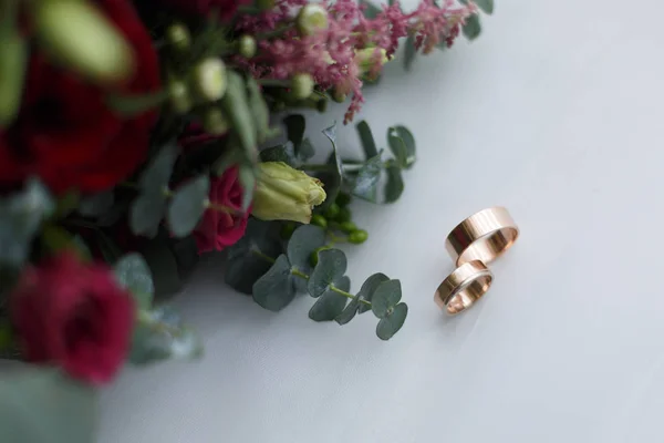 Anelli nuziali e bouquet da sposa su sfondo bianco — Foto Stock