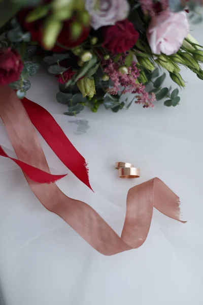 하얀 배경에 있는 결혼반지와 신부 부케 — 스톡 사진