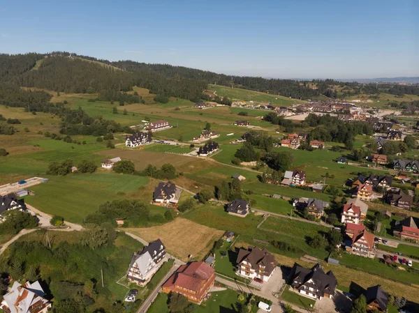 Top view of houses, road, mountains, forest and meadows