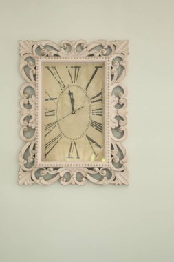 Çerçevesinde bir süs ve bir Roma d 'si olan dikdörtgen duvar saati.