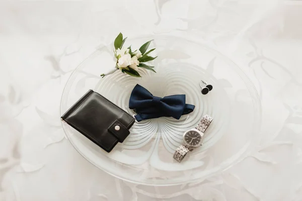 Boutonniere, manschettknappar, plånbok, klocka och slips ligger på en glasduk — Stockfoto