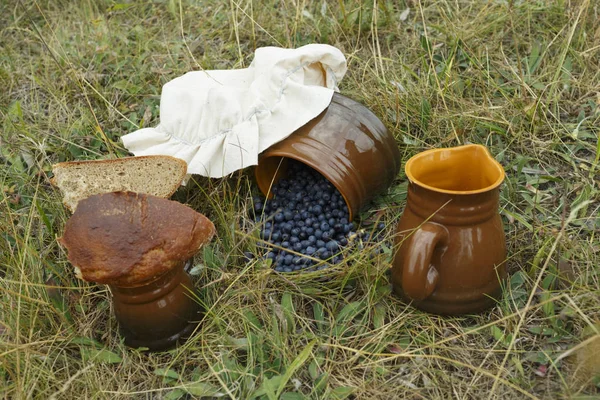 Tonkrüge und Becher vorhanden. Brot, Motorhaube und Blaubeeren im Krug — Stockfoto