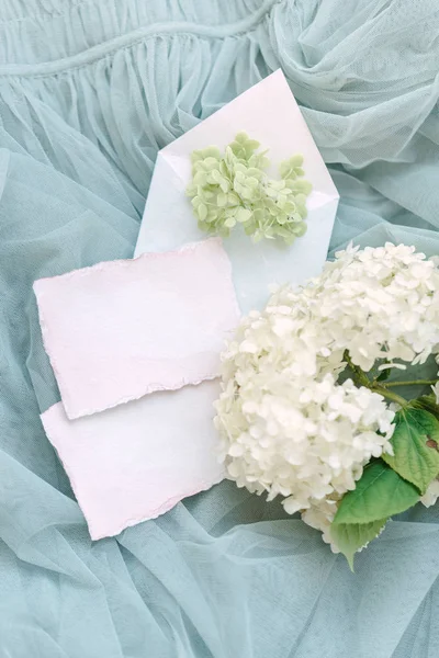 Kuvert, papper och blommor på ett turkost tyg — Stockfoto