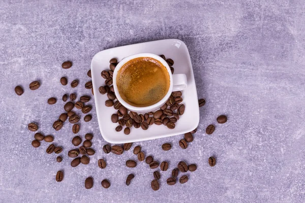 Café caliente en una taza, granos de café están dispersos cerca. Ver fro —  Fotos de Stock