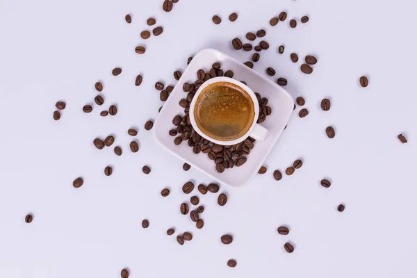 Hot coffee in a cup, coffee beans are scattered nearby. White ba — Stock Photo, Image