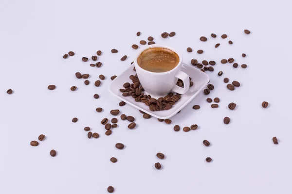 Café caliente en una taza, granos de café están dispersos cerca. Blanco ba —  Fotos de Stock