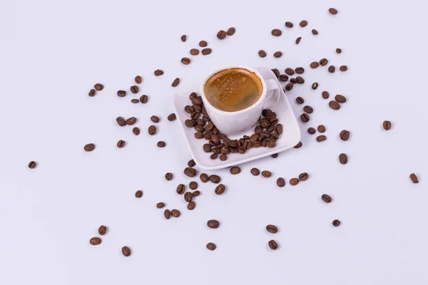 Hot coffee in a cup, coffee beans are scattered nearby. White ba — Stock Photo, Image
